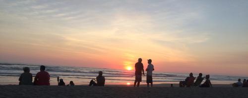 a group of people standing on the beach watching the sunset at El Reinas by Sugar's Monkey in Playa Grande