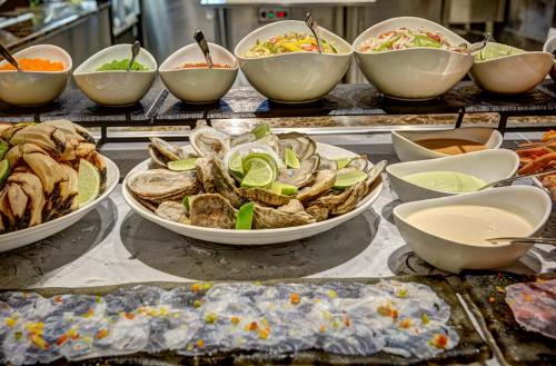 a buffet with bowls of food on a table at Royalton Bavaro, An Autograph Collection All-Inclusive Resort & Casino in Punta Cana