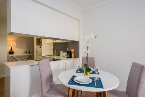 a white kitchen with a white table and chairs at 137 LuxResidence in Lisbon
