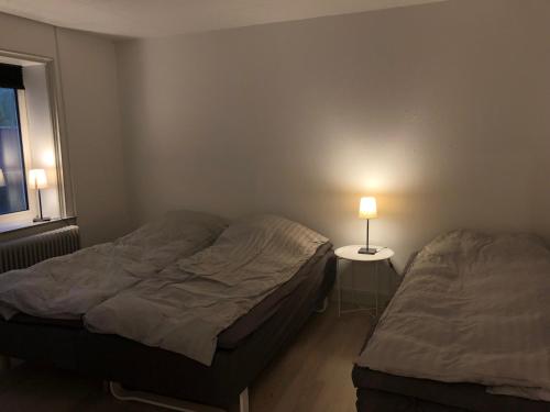 two beds in a bedroom with a lamp on a table at Hel lejlighed Thisted Midtby in Thisted