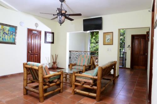 een woonkamer met stoelen en een tafel en een plafondventilator bij Hotel Aluge in Santo Domingo