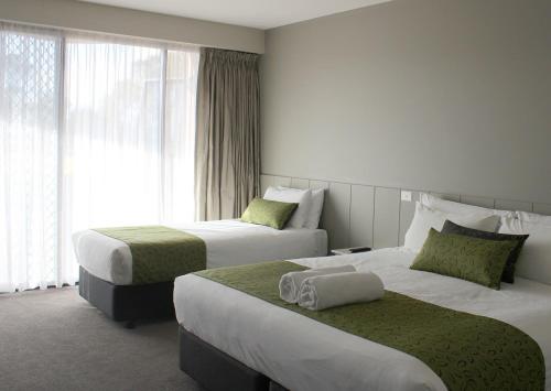 a hotel room with two beds and a window at Club Mulwala Resort in Mulwala