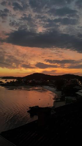 a sunset over a body of water with a city at Pousada Pedra das Tartarugas in São Francisco do Sul