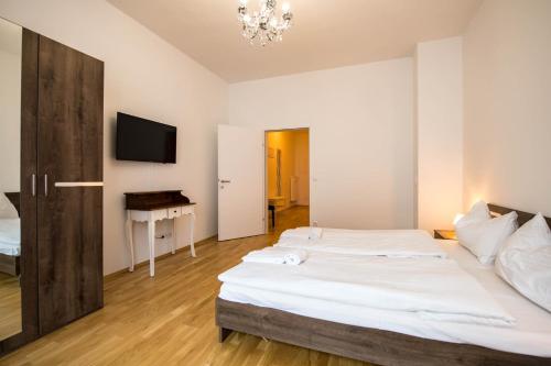 Minihotel Graz Apartments في غراتس: غرفة نوم بسريرين ومكتب وتلفزيون