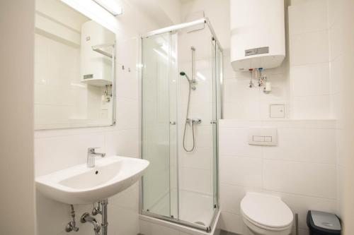 Minihotel Graz Apartments في غراتس: حمام أبيض مع حوض ودش