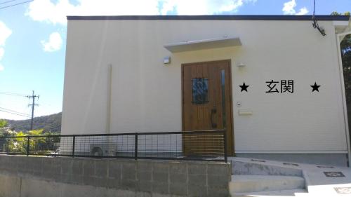 a white building with a wooden door and stars on it at Amami Mahalo in Tatsugo