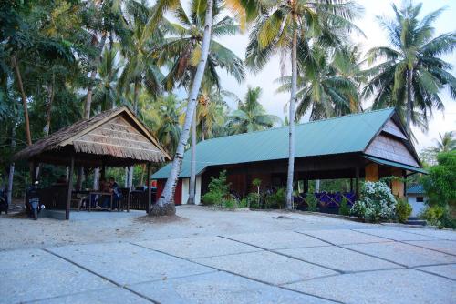 a building with a green roof and palm trees at Sunari Beach Resort 2 in Selayar