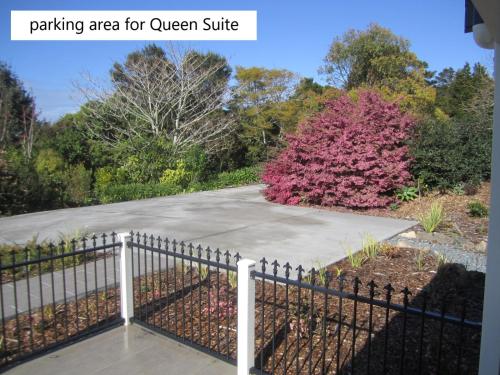 a fence in front of a garden with a pink bush at Hyecroft Lodge in Whangarei