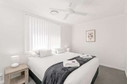 a white bedroom with a bed and a window at Wallsend on Longworth in Newcastle