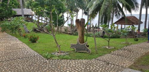 a garden with trees and a statue in the grass at Sunari Beach Resort 2 in Selayar