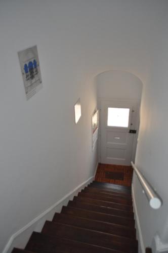 un pasillo con escaleras, una puerta blanca y una ventana en A Casa do Mestre, en Évora