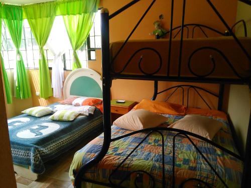 two bunk beds in a bedroom with green curtains at Casa Huespedes El Molino in Tababela
