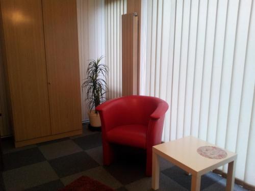 a red chair and a table in a room at Am Hallenbad Hotel garni in Ratingen