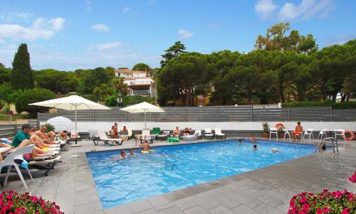 un grupo de personas sentadas alrededor de una piscina en Summer Hotel, en Calella