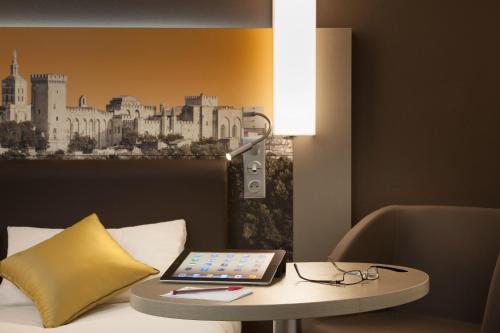 a laptop sitting on a table next to a bed at Mercure Avignon Centre Palais des Papes in Avignon