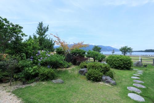 a garden with rocks in the grass and bushes at Jinpuso in Miyazu