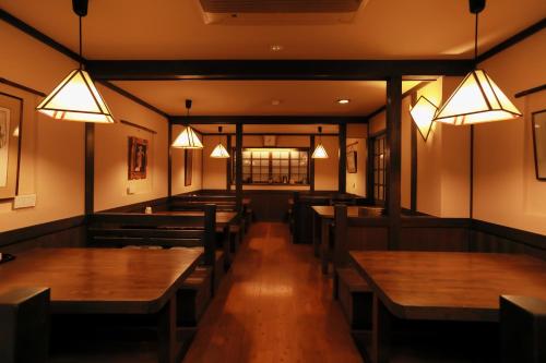 a restaurant with wooden tables and chairs and lights at Jinpuso in Miyazu