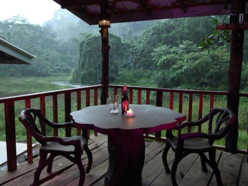 uma mesa e cadeiras num deque com vista em Explore Sinharaja Rain Forest Tour Camp em Dombagoda