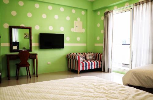 a bedroom with green walls with a chair and a mirror at England B&B in Taiping