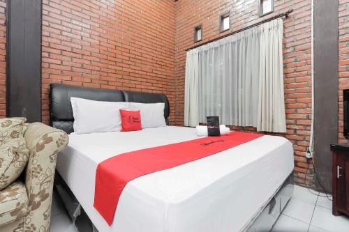 ein Schlafzimmer mit einem großen Bett und einer Ziegelwand in der Unterkunft RedDoorz @ Cilandak Timur in Jakarta