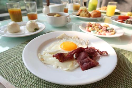 a plate of food with an egg and bacon on a table at Grand Mercure Jakarta Kemayoran in Jakarta