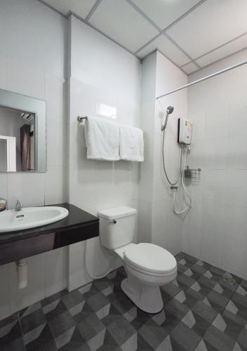 a white bathroom with a toilet and a sink at Prukpibul Apartment in Bangkok