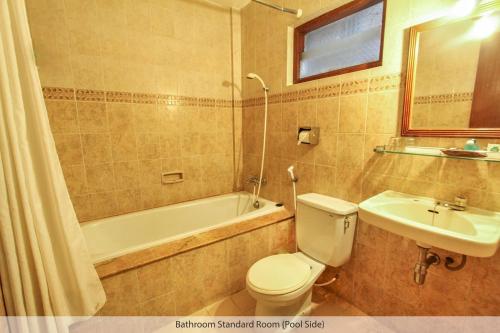 een badkamer met een toilet, een wastafel en een bad bij Duta Guest House in Yogyakarta