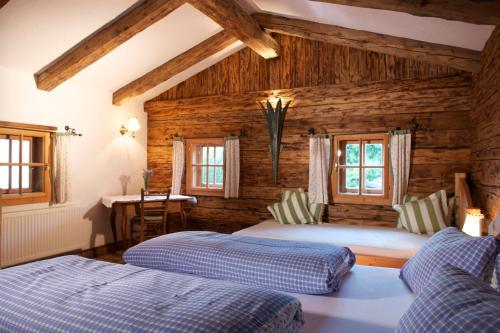 two beds in a room with wooden walls at Straganzhof in Iselsberg