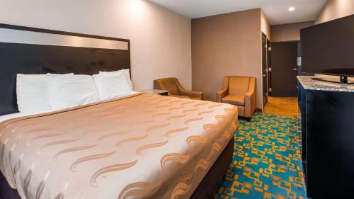 a hotel room with a large bed and two chairs at SureStay Hotel by Best Western Brownsville in Brownsville