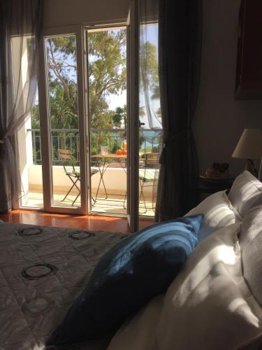 a bed with blue pillows in front of a sliding glass door at Deluxe First Line Villa in Pervolia