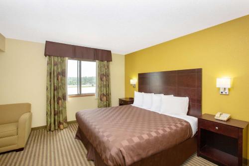 a hotel room with a bed and a chair and a window at AmericInn by Wyndham Council Bluffs in Council Bluffs