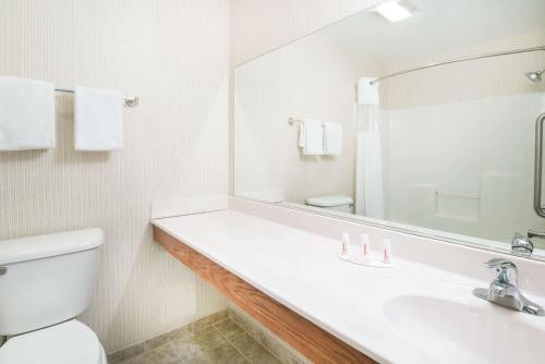 a bathroom with a sink and a toilet and a mirror at Howard Johnson by Wyndham Oacoma Hotel & Suites in Oacoma