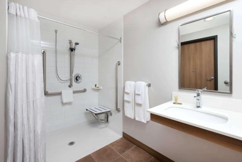 y baño blanco con lavabo y ducha. en Microtel Inn & Suites by Wyndham Sudbury, en Sudbury