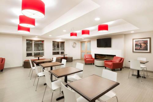 a waiting room with tables and chairs and a fireplace at Microtel Inn & Suites by Wyndham Sudbury in Sudbury