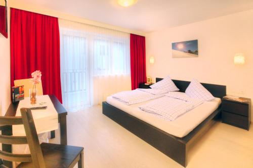 a bedroom with a bed and a desk and red curtains at Haus Pia in Sölden