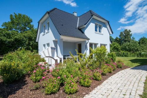 a white house with flowers in a garden at Fehmarn Mein Urlaub in Fehmarn