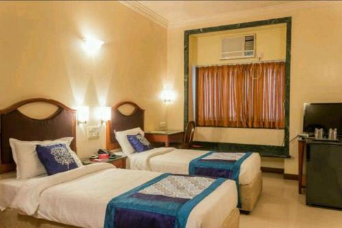 a hotel room with two beds and a television at Strand Hotel, Colaba in Mumbai