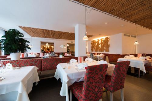 a restaurant with white tables and red chairs at Hotel Melodia del Bosco in Badia