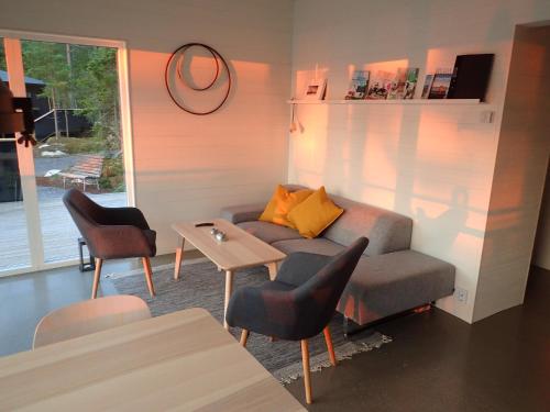 ein Wohnzimmer mit einem Sofa, Stühlen und einem Tisch in der Unterkunft Kvarnsands Strandstugor / Kvarnsand Beach Lodges in Grisslehamn