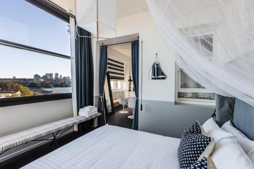a bedroom with a bed and a large window at Hotel Palisade in Sydney