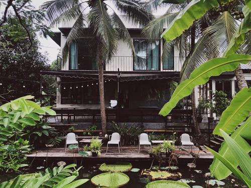 a house with chairs and a pond in front of it at Gajib Bed&Breakfast in Amphawa
