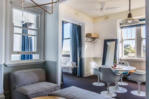 uma sala de estar com uma mesa, cadeiras e janelas em Hotel Palisade em Sidney