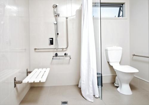 a white bathroom with a shower and a toilet at 37 The Landing Motel in Whakatane