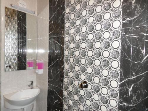 a black and white bathroom with a sink and a mirror at Hotel Grand Ganesha in Ganpatipule