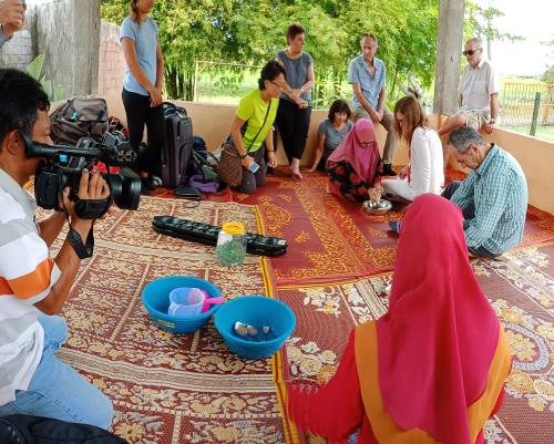 a group of people sitting on the ground with a camera at Homestay Damai Sri Kota in Kepala Batas