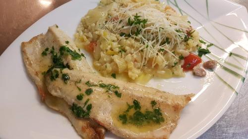 a plate of food with a piece of fish and pasta at Landgasthof Trattnig in Schiefling am See
