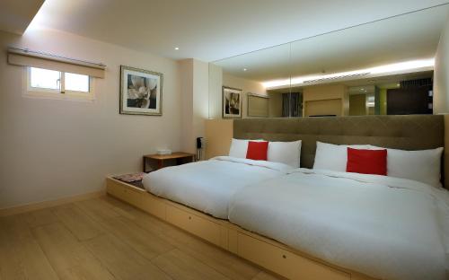 a bedroom with a large white bed with red pillows at Crystal Inn Sun Moon Lake in Yuchi