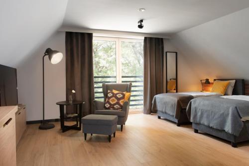 sypialnia z dwoma łóżkami, krzesłem i oknem w obiekcie Apartamenty Centrum Park Sowińskiego 19 w Zielonej Górze