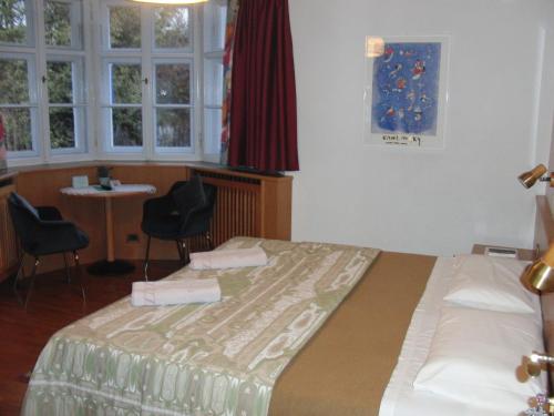 a bedroom with a bed and a desk and windows at Hotel Villa Emilia in Ortisei