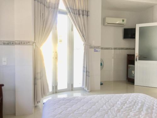 a bedroom with a bed and a large window at NGỌC QUÝ Mini House in Quy Nhon